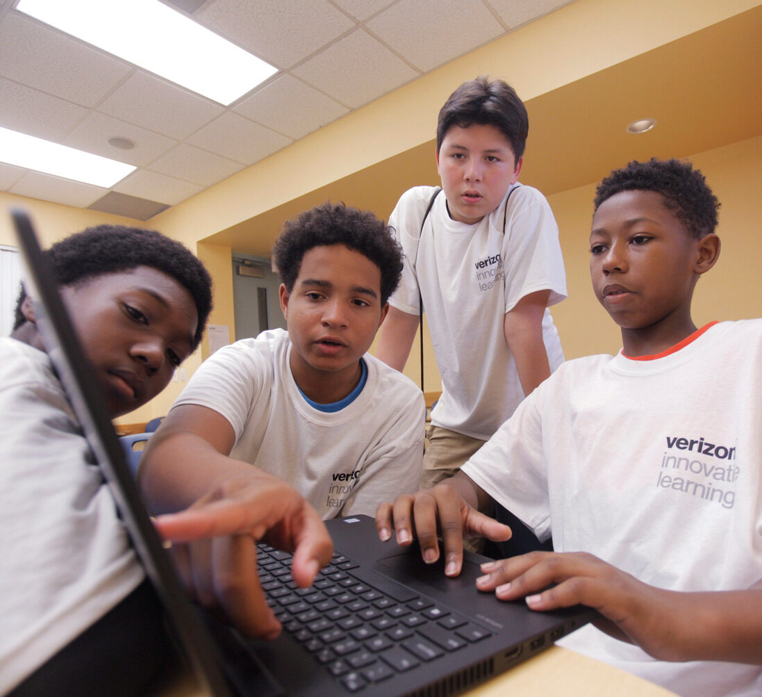 four middle school boys look at a laptop